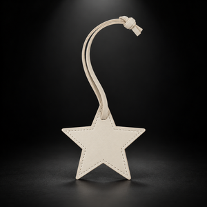 Ivory star bag charm on black spotlight background