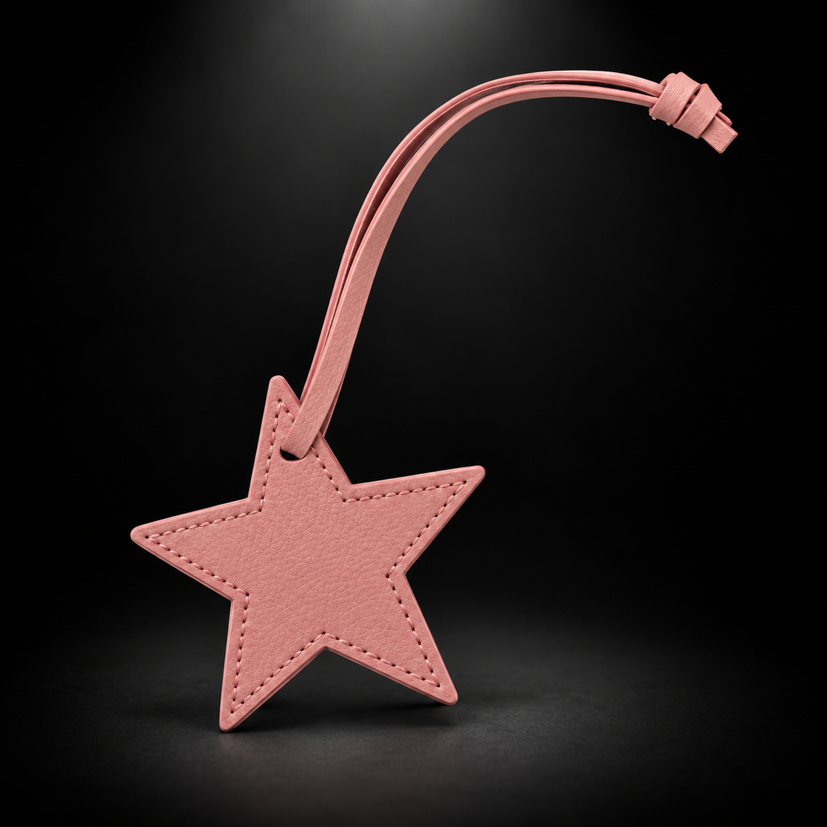 Pink star bag charm on black spotlight background